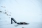 A person full submerged in a cold plunge, with snow fall.